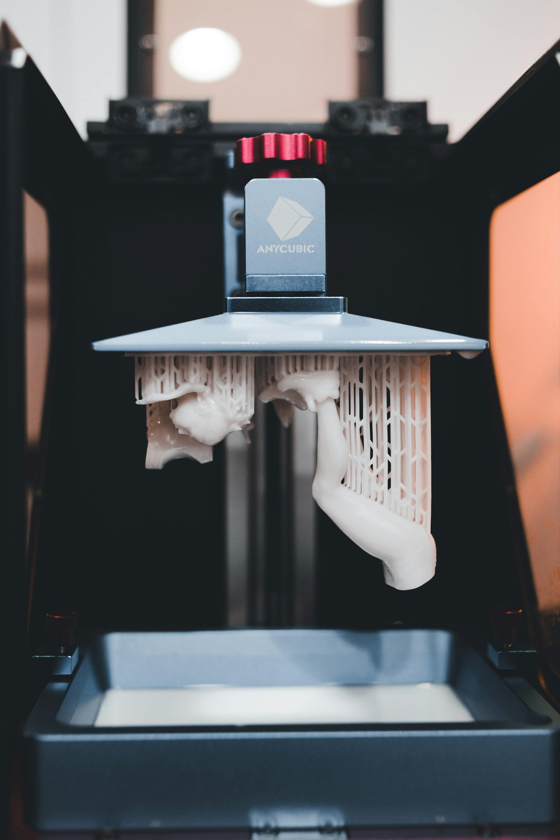Photo of a resin 3d printer with a print still on the bed